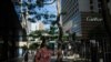 Pedestrians wear face masks as they walk past high-end fashion shops in the Central district of Hong Kong on July 16, 2020.