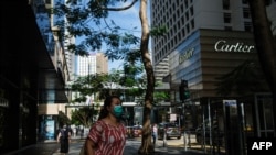 Pedestrians wear face masks as they walk past high-end fashion shops in the Central district of Hong Kong on July 16, 2020.