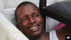 A young man suspected of being a militant supporter of opposition candidate Etienne Tshisekedi reacts in fear as police threaten to kill him, as he lies on the floor of a police truck after being arrested near opposition party headquarters in the Limete d