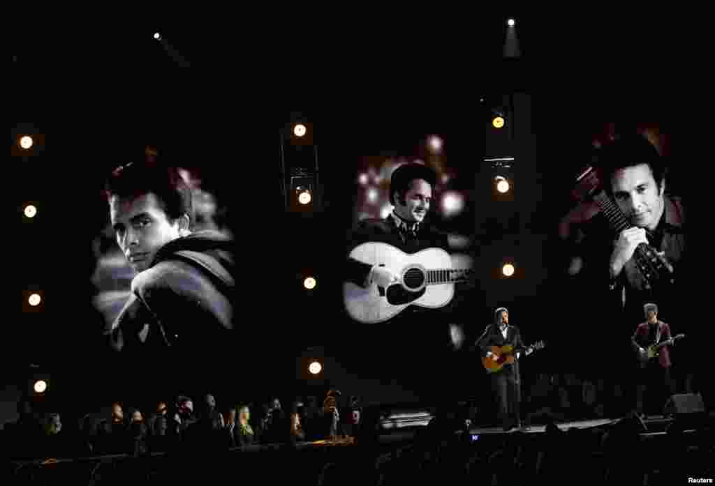 Vince Gill (kiri) dan Ben Haggard menyanyikan lagu &quot;Mama Tried&quot; dengan latar &nbsp;belakang foto-foto Merle Haggard saat muda pada acara Country Music Association Awards ke-50 di Nashville, Tennessee (2/11). Ikon musik country itu meninggal dunia pada ulang tahunnya yang ke-79 pada 6 April 2016 setelah lama sakit. (Reuters/Harrison McClary)