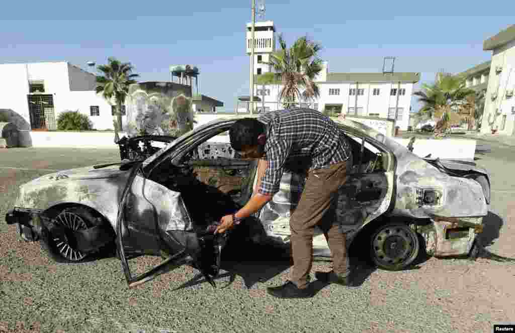 A military personnel examines a car, which exploded near a women's police academy, in Tripoli August 19, 2012. 