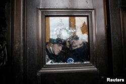 Members of the Capitol Police look through a smashed window as pro-Trump protesters rally to contest the certification of the 2020 U.S. presidential election results by the U.S. Congress, at the U.S. Capitol Building in Washington, Jan. 6, 2021.