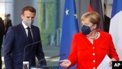 German Chancellor Angela Merkel and French President Emmanuel Macron give a joint statement to journalists, at the chancellery in Berlin, June 18, 2021. 