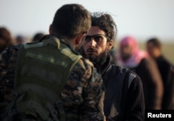 A fighter from Syrian Democratic Forces checks a man near the village of Baghuz, Deir Al Zor province, Syria, Feb. 22, 2019.