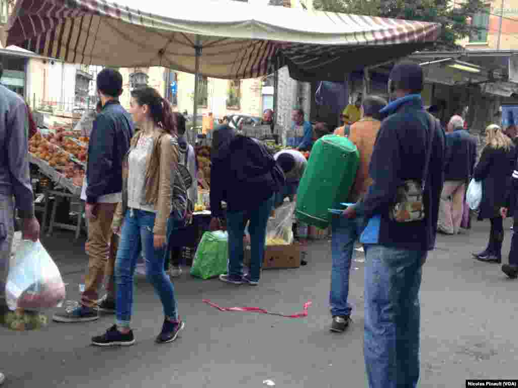 Un Sénégalais distribue des tracts au marché de Lima, Milan, 10 octobre 2015 (Nicolas Pinault/VOA).