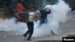 An anti-government protester throws tear gas canister fired by riot police during clashes after the funeral procession of Ali Abbas and Ahmed Al Mesjen who died when their car exploded in the village of Maqsha west of Manama, April 22, 2014. 