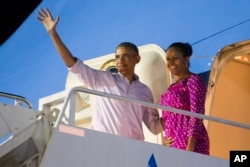 FILE - President Barack Obama, left, and first lady Michelle Obama wave as they board Air Force One to depart from Joint Base Pearl Harbor-Hickam at the end of their family vacation, Jan. 2, 2016, in Honolulu, Hawaii.