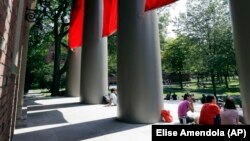 People sit outside at Harvard University in Cambridge, Massachusetts, where dozens of students were investigated for cheating in 2012 after school officials discovered evidence they may have wrongly shared answers or plagiarized on a final exam.