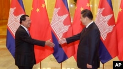 Cambodia's Prime Minister Hun Sen (L) stretches to shake hands with China's President Xi Jinping before a meeting at the Great Hall of the People in Beijing, November 7, 2014. REUTERS/Jason Lee/POOL