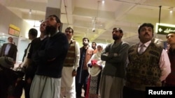 7일 파키스탄 라왈핀디의 국제 공항에서 여행객들이 비행기 추락 소식을 범하는 TV 뉴스를 시청하고 있다.