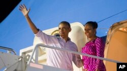 Presiden Barack Obama, kiri, dan ibu negara Michelle Obama saat menaiki pesawat Air Force One untuk kembali ke Washington dari Pangkalan Gabungan Pearl Harbor-Hickam setelah libur natal, 2 Januari 2016, di Honolulu, Hawaii.