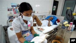 A nurse, wearing protective mask and gloves reads to a HIV/AIDS patient at the Phra Baht Nam Phu AIDS hospice near Lopburi, Thailand (File)