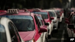 FILE - Taxi drivers block the roundabout at the Angel of Independence monument to demand equal conditions with rideshare services, in Mexico City, Oct. 12, 2020. 