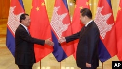 Cambodia's Prime Minister Hun Sen (L) stretches to shake hands with China's President Xi Jinping before a meeting at the Great Hall of the People in Beijing, November 7, 2014. REUTERS/Jason Lee/POOL