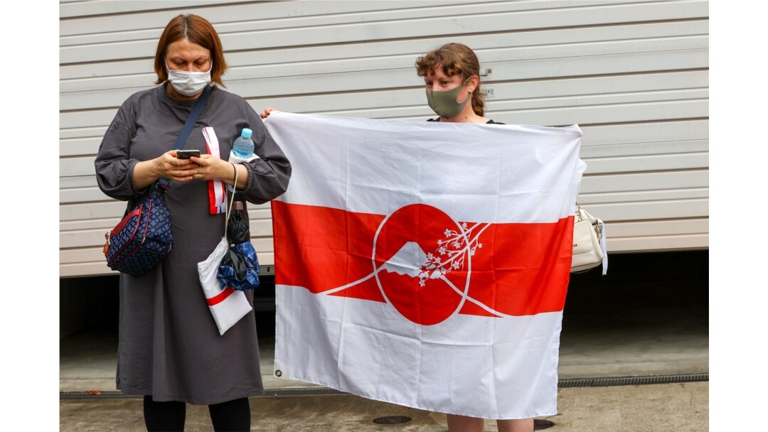 Seorang wanita Belarusia memegang bendera saat sprinter Krystsina Tsimanouskay tiba di kedutaan Polandia di Tokyo, Jepang, 2 Agustus 2021. (REUTERS/Kim Kyung-Hoon)