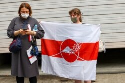 Seorang wanita Belarusia memegang bendera saat sprinter Krystsina Tsimanouskay tiba di kedutaan Polandia di Tokyo, Jepang, 2 Agustus 2021. (REUTERS/Kim Kyung-Hoon)