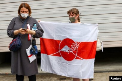 Seorang wanita Belarusia memegang bendera saat sprinter Krystsina Tsimanouskay tiba di kedutaan Polandia di Tokyo, Jepang, 2 Agustus 2021. (REUTERS/Kim Kyung-Hoon)