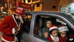 A Palestinian man dressed as Santa Claus stands near a car as he hands out Christmas presents to children in the West Bank city of Bethlehem, ahead of Christmas, 20 Dec 2010