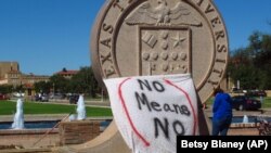FILE - In this 2014 photo, aTexas Tech student drape a bed sheet with the message "No Means No" over the university's seal at the Lubbock, Texas campus.