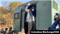 Defiant journalist Hopewell Chin'ono raises his fist to colleagues, relatives and friends while getting into a waiting prison vehicle July 23, 2020, outside Harare Magistrates Court after saying he would not be 'bowed' from talking about corruption becau