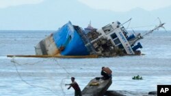 A fisherman throws his net beside the half-submerged M/V Palawan Pearl after it collided with a Cyprus-flagged BKM 104 dredger in Manila bay, Philippines.