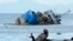 A fisherman throws his net beside the half-submerged M/V Palawan Pearl after it collided with a Cyprus-flagged BKM 104 dredger in Manila bay, Philippines.