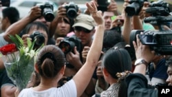 A woman flashes a three-fingered salute borrowed from "The Hunger Games" during an anti-coup demonstration outside the Australian Embassy in Bangkok, Thailand Wednesday, June 4 , 2014