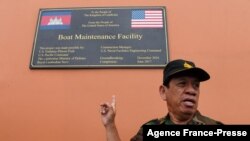 Cambodia's Ministry of Defense spokesperson Chhun Socheat shows a sign donated by the US during a government organized media tour to the Ream naval base in Preah Sihanouk province on July 26, 2019. 