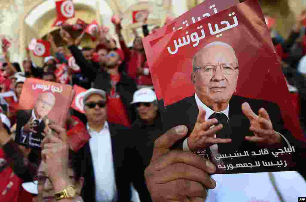 Pendukung calon Presiden Tunisia, Beji Caid Essebsi (seperti terlihat di potret), meneriakkan slogan-slogan dan melambaikan bendera-bendera di Bourguiba Avenue di ibukota Tunis, dalam sebuah kampanye pemilihan presiden mengawali pemilu yang diadakan pada 23 November. &nbsp;