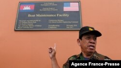 Cambodia's Ministry of Defense spokesperson Chhun Socheat shows a sign donated by the US during a government organized media tour to the Ream naval base in Preah Sihanouk province on July 26, 2019. 