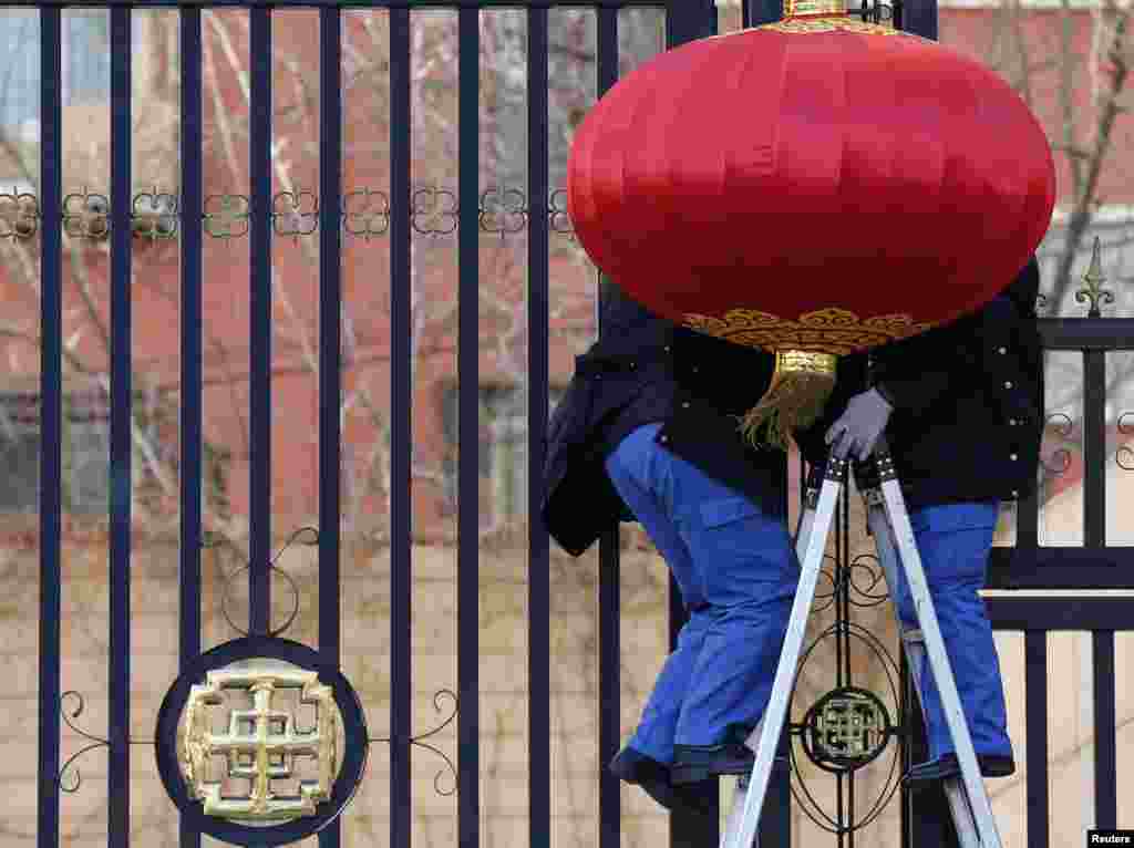 Workers hang up a large red lantern for decoration outside the gate of an apartment building to prepare for Chinese Lunar New Year celebrations in Beijing, China.