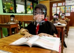 인도네시아 자카르타 초등학교가 대면 수업을 재개한 가운데 학생들이 신종 코로나바이러스 예방을 위한 마스크와 안면보호대를 쓰고 수업을 듣고 있다.