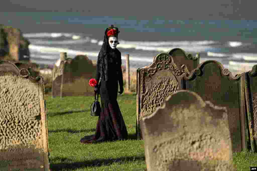 A participant in costume walks between the gravestones in St. Mary&#39;s church graveyard during the biannual &#39;Whitby Goth Weekend&#39; festival in Whitby, northern England.