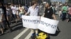 Protesters stand on a portrait of Russian President Vladimir Putin during an opposition rally in Moscow, Russia, Sunday, July 29, 2018. Banners read from left: "Get old", "Be quiet". 