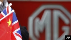 An MG employee holds Chinese and British flags during a visit by Chinese Premier Wen Jiabao to the MG motor plant in Birmingham, central England, Sunday, June 26, 2011.