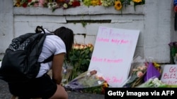 연쇄총격 사건이 일어나 미국 애틀랜타의 '골드스파' 앞에서 18일 한 여성이 희생자들을 추모하는 꽃을 놓고 있다.