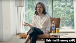 South Korean actor Youn Yuh-jung “Minari” sits in the beer company Oriental Brewery's latest advertising campaign. (Oriental Brewery via AP)