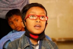 Ridowan from Kutupalong reads the eye chart with his first pair of glasses at the Kutupalong Government Primary School, Feb. 13, 2020. (Hai Do/VOA)