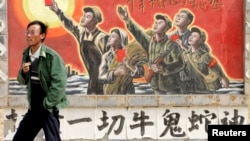 资料照：一名男子走过宁夏银川街头郊区的一处描写中国文革的宣传画。（2007年4月25日）