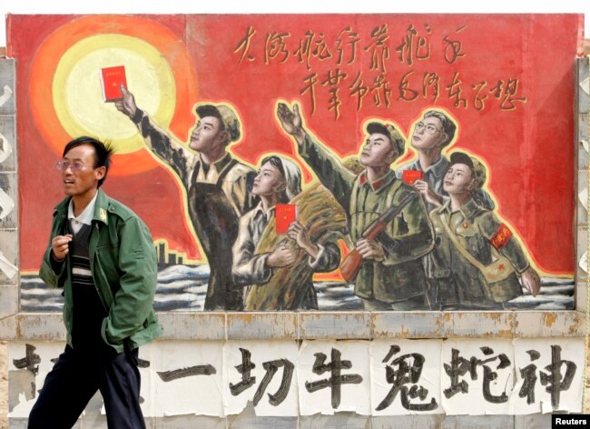 资料照：一名男子走过宁夏银川街头郊区的一处描写中国文革的宣传画。（2007年4月25日）
