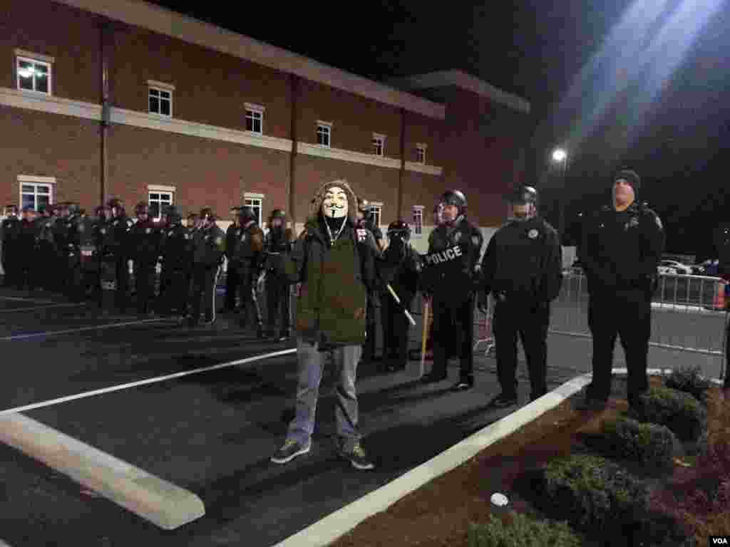 A protester in a mask poses in front of the Ferguson police. He was later arrested, Nov. 19, 2014. (Ayesha Tanzeem/VOA)