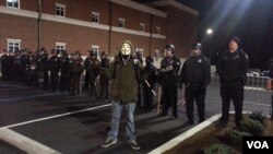 Un manifestante en máscara de Anonymus posa frente a la policía de Ferguson. Él fue uno de los arrestados del miércoles. (Ayesha Tanzeem/VOA)