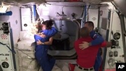 In this frame grab from NASA TV, astronaut Shannon Walker, second from left, is greeted by astronaut Kate Rubins, left, as she enters the International Space Station after arriving from the SpaceX Dragon capsule, early Tuesday, Nov. 17, 2020.