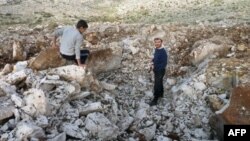 Syrian men stand inside crater where they said Scud missile landed December 13, 2012