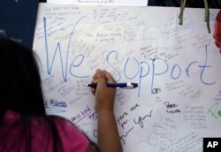 Jasmine Ruiz writes a note at a makeshift memorial in front of the police department in Dallas, July 9, 2016. Five police officers were killed in a shooting in downtown Dallas on Thursday.