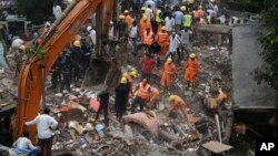 Petuga penyelamat membersihkan reruntuhan bangunan berlantai lima yang runtuh di Ghatkopar, Mumbai, India, Selasa (25/7). 