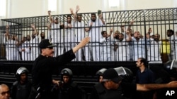 Supporters of the Muslim Brotherhood and other Islamists gesture from the defendants cage as they receive sentences after they were convicted of murder, rioting, and violence in a mass trial in Alexandria, Egypt, May 19, 2014.