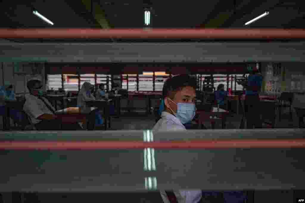 A high school student wears a face mask in a classroom on the first day after being reopened following restrictions to halt the spread of the COVID-19 coronavirus in Kuala Lumpur.