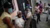 Residentes ayudan a descargar bolsas de alimentos básicos, como pasta, azúcar, harina y aceite de cocina, proporcionados por un programa de asistencia alimentaria del gobierno, en el barrio Santa Rosalía de Caracas, Venezuela, el sábado 10 de abril 2021.