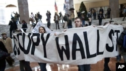 Protesters affiliated with the Occupy Wall Street movement hold up a sign in the center of Winter Garden Atrium in Three World Financial Center, New York, New York, December 12, 2011.